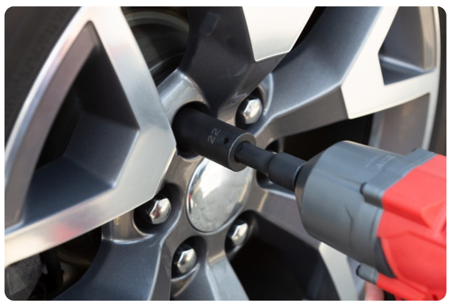 A person tightening a tire using a drill, demonstrating mechanical skills and attention to vehicle maintenance.