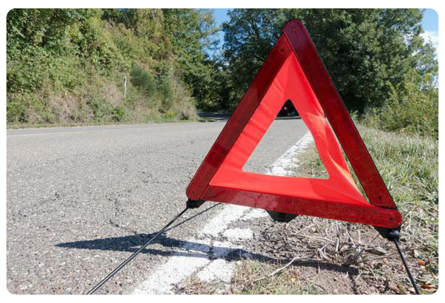A red triangle warning sign positioned on the roadside, indicating caution for approaching vehicles.