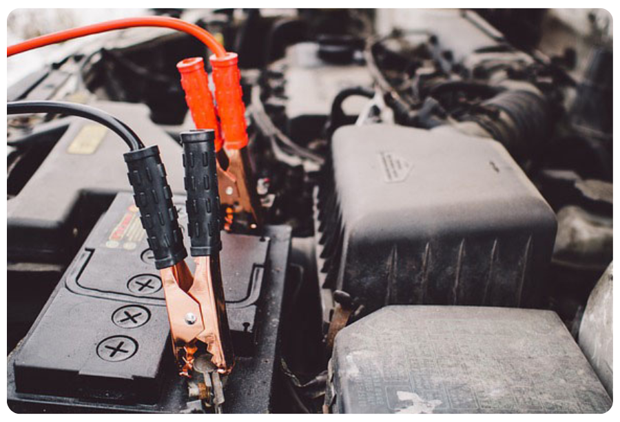 A car battery with two wires attached, illustrating a connection for power transfer or charging.