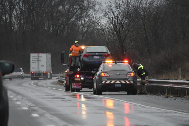 Emergency towing company assisting a vehicle on a rainy highway roadside.