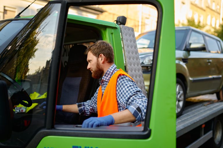 Certified towing company driver operating a flatbed tow truck.