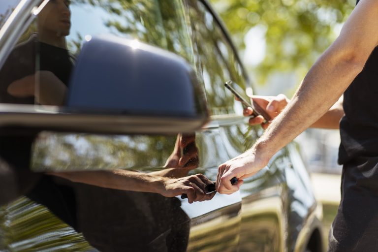 A man using smartphone for keyless car entry, a convenient way to avoid the need for auto lockout service.