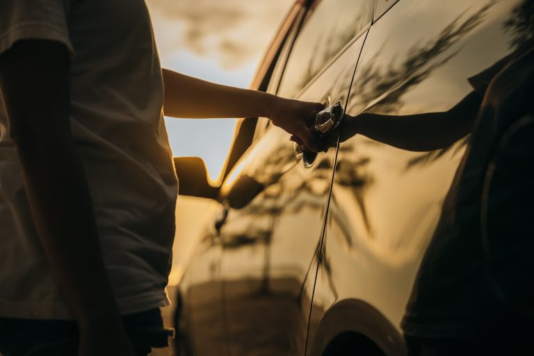 A person trying to open a car door with no success, highlighting the need to avoid the hassle of an auto lockout service.